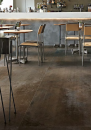 Restauracja w stylu industrialnym ze stolikami oraz krzesłami i podłogą w płytki imitujące metal w kolorze brązowym Florim Architectural Design Flowtech Aged Bronze Naturale 60x120