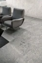 Pomieszczenie z fotelami wypoczynkowymi i płytkami podłogowymi imitującymi kamień, w kolorze szarym Florim Architectural Design Plimatech Plimagray/01 Naturale/Matte 60x120