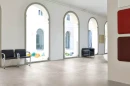 Nowoczesne pomieszczenie z dużymi oknami, czarnymi krzesłami i płytkami podłogowymi imitującymi beton Florim Architectural Design Rawtech Raw-White Naturale