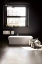 Łazienka z czarną ścianą, białą wanną wolnostojącą, dużym oknem i płytkami podłogowymi imitującymi beton Florim Architectural Design Rawtech Raw-White Naturale 80x80