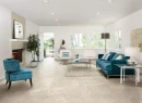 Nowoczesny salon z kominkiem, meblami wypoczynkowymi w kolorze białym i turkusowym oraz płytkami podłogowymi imitującymi marmur Florim Contemporary Design Exalt Amber Symphony Naturale