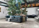 Nowoczesne wnętrze z dużą rośliną, czarnymi meblami wypoczynkowymi oraz płytkami podłogowymi imitującymi kamień Florim Contemporary Design Rock Salt Danish Smoke