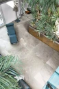 Nowoczesne wnętrze z roślinami, turkusowym leżakiem oraz płytkami podłogowymi imitującymi kamień Florim Contemporary Design Rock Salt Danish Smoke