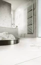 Nowoczesna jasna łazienka z ozdobną ścianą, wanną, srebrną baterią wannową, wiszącym grzejnikiem i płytkami imitującymi marmur Florim Contemporary Design Timeless Calacatta