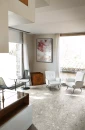 Salon z dużymi oknami, białymi fotelami, krzesłami i stolikiem oraz płytkami podłogowymi Florim Contemporary Design Timeless Ceppo di Grè