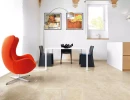 Nowoczesne wnętrze z białym stołem, czarnymi krzesłami i pomarańczowym fotelem oraz płytkami podłogowymi Florim Contemporary Design Timeless Marfil