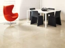 Nowoczesne wnętrze z białym stołem, czarnymi krzesłami i pomarańczowym fotelem oraz płytkami podłogowymi Florim Contemporary Design Timeless Marfil