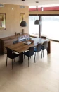 Jadalnia z drewnianym stołem, czarnymi krzesłami, czarnymi lampami wiszącymi, drewnianą komodą i płytkami podłogowymi Florim Contemporary Design Timeless Travertino