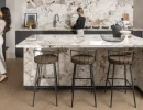 Nowoczesna kuchnia z marmurową wyspą, krzesłami barowymi - hokerami, drewnianą podłogą i płytkami Florim Creative Design Nature Mood Tundra
