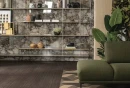 Salon z zieloną kanapą, płytkami drewnopodobnymi na podłodze Florim Creative Design Nature Mood Plank_03, ozdobnym regałem i płytkami na ścianie imitującymi marmur Florim Creative Design Nature Mood Riverbed