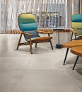 Salon z fotelami, drewnianym stolikiem kawowym oraz płytkami podłogowymi imitującymi beton Florim Creative Design Studios Cloud