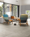Salon z dużymi oknami, jasną kanapą i fotelami oraz płytkami podłogowymi imitującymi beton Florim Creative Design Studios Cloud