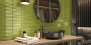Łazienka z wyklejoną mozaiką Barwolf Stripes Reed Green Glossy KIT-23005 29,6x29,6 na ścianie. Drewniane meble łazienkowe z grafitową umywalką wolnostojącą oraz grafitową baterią. Okrągłe lustro z grafitową ramą.