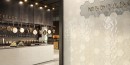 Restauracja z płytkami Barwolf Loft Latte White Matt KE-22102 13,7x15 wyłożonymi na ścianie. Na podłodze płytki z jasnego lastryko i kolorowymi małymi kamyczkami.
