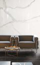 Wnętrze z brązowymi fotelami, złotym stolikiem, podłogą drewnopodobną i płytkami na ścianie imitującymi marmur Florim Luxury Design I Classici Statuario