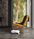 Pomieszczenie z ozdobną ścianą, fotelem, dużym oknem i podłogą imitującą kamień Florim Luxury Design La Roche Mud