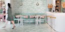 Kontura kawiarni wyłożony białą boazeria, stoliki z białymi nogami i drewnianym blatem. Podłoga oraz ściany wyłożona płytkami Barwolf Wallpaper Silky Jade Green SIL-21103 18,5x18,5
