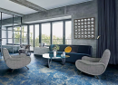 Salon z dużymi oknami, betonową ścianą, niebieską kanapą, fotelami i płytkami podłogowymi imitującymi marmur Florim Luxury Design Les Bijoux Sodalite Bleu