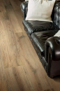 Pomieszczenie ze skórzaną czarną sofą i płytkami podłogowymi drewnopodobnymi Florim Luxury Design Planches Noisette