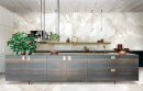Kuchnia z wyspą z drewnianymi szafkami, wiszącą półką i płytkami na ścianie i podłodze imitującymi marmur Florim Luxury Design Reves Reve Perle