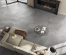 Salon z jasną kanapą, kominkiem oraz płytkami podłogowymi imitującymi kamień Leonardo Ceramica Ashima ASHM RB12G RM