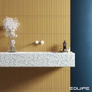 Łazienka wyłożona płytkami Equipe Hopp Golden 5x40, blat z umywalką wykonany z jasnego lastryko z czarnymi kropkami, podtynkowa, biała bateria umywalkowa