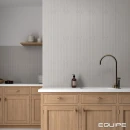 Płytka Equipe Hopp Bro Grey 5x40 wyłożona na ścianie kuchni powyżej jasnego blatu położonego na drewnianych szafkach kuchennych