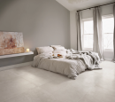 Jasna sypialnia z dużym łóżkiem i płytkami podłogowymi imitującymi beton Leonardo Ceramica Moon 90W RM