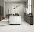 Kuchnia w stylu glamour z szarymi meblami kuchennymi, czarnym blatem roboczym - konglomerat, złotymi krzesłami typu hoker, ozdobną sztukaterią na ścianach i płytkami podłogowymi oraz na wyspie imitującymi marmur Leonardo Ceramica One QUA SW