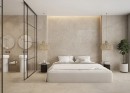 Sypialnia z łazienką w loftowym stylu wyłożone płytkami Halcon Aura Sand Natural 60x60 na ścianach i podłodze, duże dwuosobowe łóżko, przeszklona ścianka z czarnymi szprosami oddziela sypialnię i łazienkę