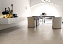 Pomieszczenie w stylu industrialnym ze stołem, jasnymi fotelami, białą szafką wiszącą i płytkami podłogowymi lastryko Leonardo Ceramica Overcome OVRC 60GB