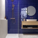 Łazienka z płytkami Equipe Fango Cobalt Gloss 5x15 wyłożonymi na ścianie, przeszklona kabina prysznicowa typu walk-in, okrągłe lustro w czarnej ramie powyżej szafki łazienkowej w jasnym kolorze z umywalką nablatową