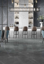 Wnętrze restauracji w stylu glamour, z białą marmurową ladą, wiszącą lampą, krzesłami barowymi i szarymi płytkami imitującymi marmur Alfalux Canova Greystone