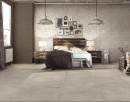 Sypialnia z łóżkiem, ozdobną tapetą na ścianie, lampami wiszącymi oraz płytkami podłogowymi imitującymi beton Alfalux Materika Grigio