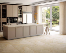 Nowoczesna kuchnia w kolorach taupe, z beżowymi frontami, wyspą, dużymi oknami tarasowymi oraz płytkami podłogowymi imitującymi kamień Alfalux Stonequartz Beige