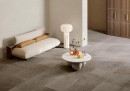 Salon wyłożony płytkami Fioranese Autentica Grey Naturale 30,2x60,4 AU364R, biała kanapa, wolnostojąca lamka oraz stolik w białym kolorze