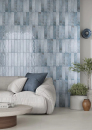 Pomieszczenie z jasną kanapą, stolikiem kawowym, betonową podłogą oraz ozdobnymi płytkami na ścianie - niebieskimi  cegiełkami Paradyż Ceramika Monpelli Blue Mix 6,5x29,8