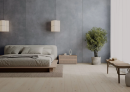 Sypialnia w stylu loftowym z łóżkiem, drewnianą podłogą i ścianą z płytkami imitującymi beton, w kolorze szarym, w matowym wykończeniu Paradyż Ceramika Architeq Graphite Mat