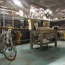 Sklep rowerowy w stylu industrialnym z odzieżą kolarską, zielone płytki podłogowe imitująca metal z widocznym efektem rdzy Caesar Alchemy TC. Mint