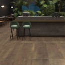 Nowoczesne wnętrze restauracji z ozdobną roślinnością, ladą barową oraz płytkami podłogowymi imitującymi metal Flaviker Rebel Brass Naturale