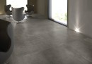 Pomieszczenie z fotelami wypoczynkowymi oraz grafitowymi płytkami podłogowymi imitującymi beton Fondovalle Portland Tabor Natural