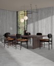 Jadalnia z długim drewnianym stołem, krzesłami, szarymi płytkami imitującymi trawertyn na ścianie Fondovalle Royal Travertino Griseo Vein Matt oraz na podłodze Griseo Cross Mat