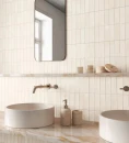 Ścienna dekoracyjna płytka Gayafores Deco Biscuit Almond 32x62,5 wyłożona na ścianie łazienki. Kamienne umywalki postawione na marmurowym podwieszanym blacie. Podtynkowe baterie umywalkowe