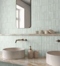 Ścienna dekoracyjna płytka Gayafores Deco Biscuit Green 32x62,5 wyłożona na ścianie łazienki. Kamienne umywalki postawione na marmurowym podwieszanym blacie. Podtynkowe baterie umywalkowe