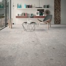 Salon z szarymi płytkami podłogowymi imitującymi kamień, lastryko Mirage Norr Vit RR 01