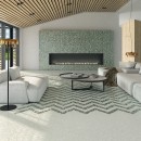 Aranżacja salonu z drewnianymi lamelami sufitowymi, ozdobnym kominkiem, stolikiem kawowym, jasnymi meblami wypoczynkowymi oraz zielonymi płytkami Arcana Spuma Sorbetto Menta oraz białymi Arcana Spuma Sorbetto Panna z efektem mieszania farby