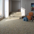 Wnętrze holu z dużym oknem, brązowym fotelem, schodami i płytkami podłogowymi imitującymi beton z efektem mieszania farby Arcana Spuma-R Tutti Frutti