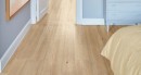 Sypialnia wyłożona płytkami drewnopodobnymi Marazzi Alma Beige 20x120 cm MFDD z szarą szafką w rogu