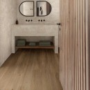 Łazienka wyłożona płytkami drewnopodobnymi Marazzi Alma Marrone 20x120 MFDF, z dwoma lustrami, czarną armaturą oraz półką na ręczniki