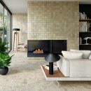 Salon z kominkiem, w którego centrum stoi biała kanapa oraz matowymi, beżowymi płytkami imitującymi kamień Marazzi Caracter Mix Beige